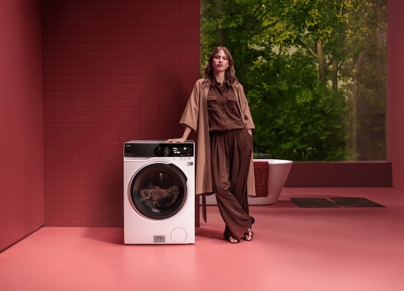 Woman standing next to washing machine.