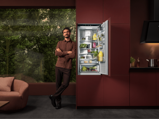 Man standing next to a fridge in a kitchen.