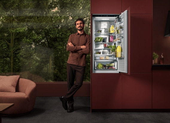 Man standing next to a fridge in a kitchen.